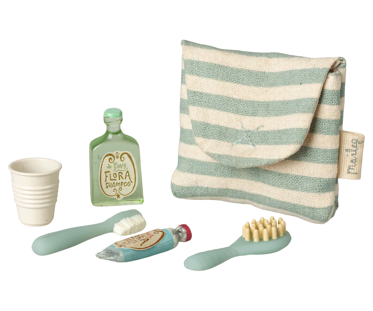 Set of children's dental care items including a cup, toothbrush, and toothpaste with a striped pouch on a white background.