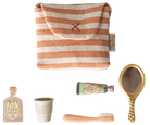 Set of travel-sized products including a striped pouch, bottle, cup, brush, and mirror on a white background.