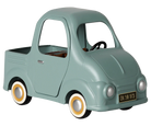 A retro-style toy pickup truck in a muted sage green color, featuring yellow-rimmed white wheels, a black steering wheel, and a small license plate reading 'DK 56 915'.