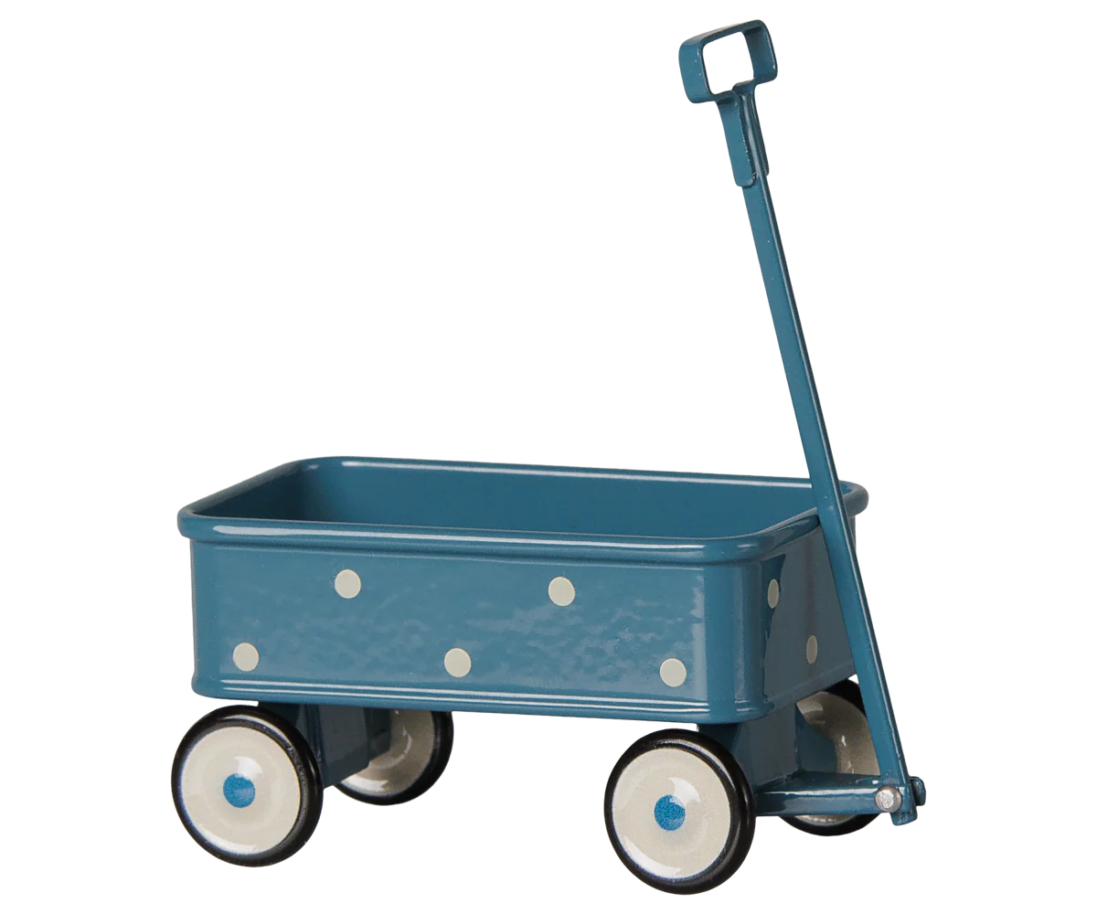 A vintage-style metal toy wagon in a muted teal blue color, decorated with white polka dots, featuring four wheels with white and black tires and blue centers, and a matching blue handle.