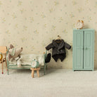 MAileg Miniature bedroom setup with a bed, chair, coat, and wardrobe against a floral wallpapered wall.