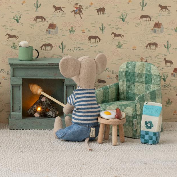 Miniature room setup with furniture and a mouse character in front of a fireplace, against a wallpapered wall.