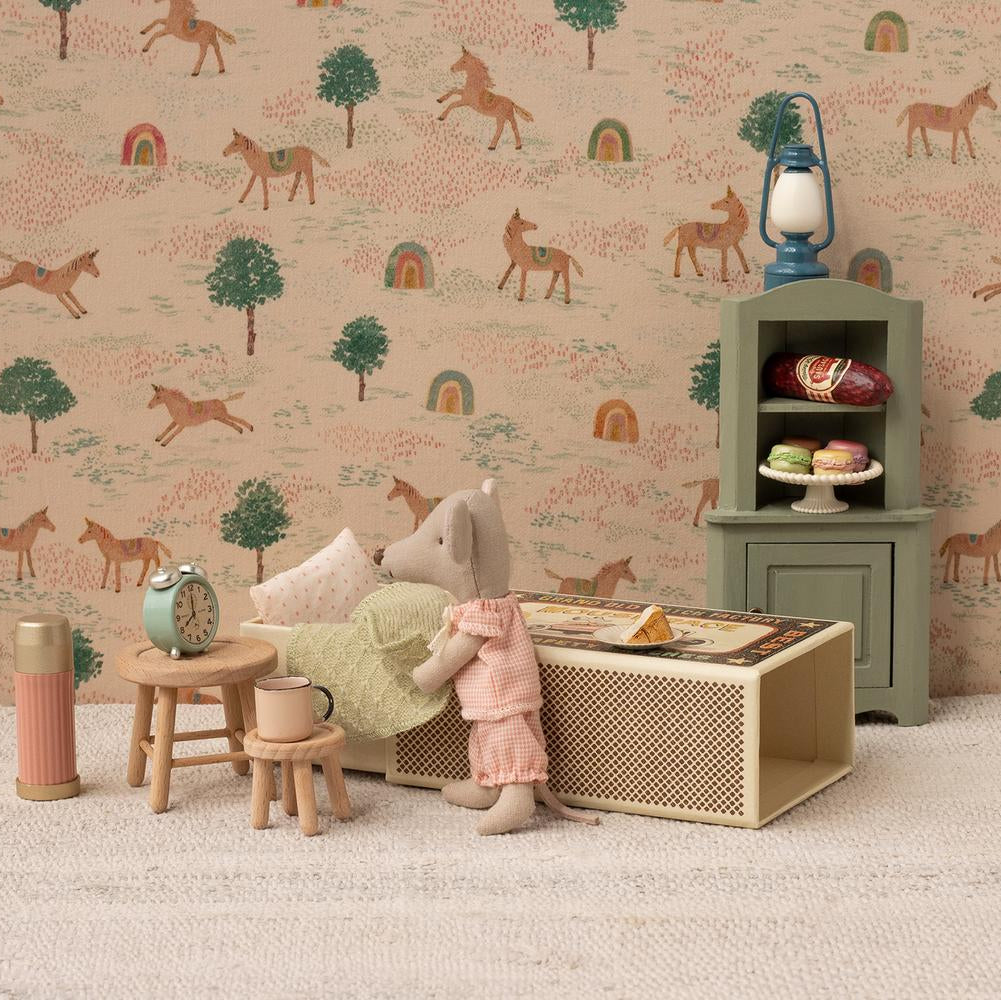 Miniature Maileg dollhouse scene with a girl mouse, furniture, and decorative elements against a patterned wallpaper.
