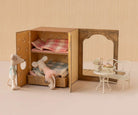 Miniature dollhouse with furniture and plush toys on a neutral background