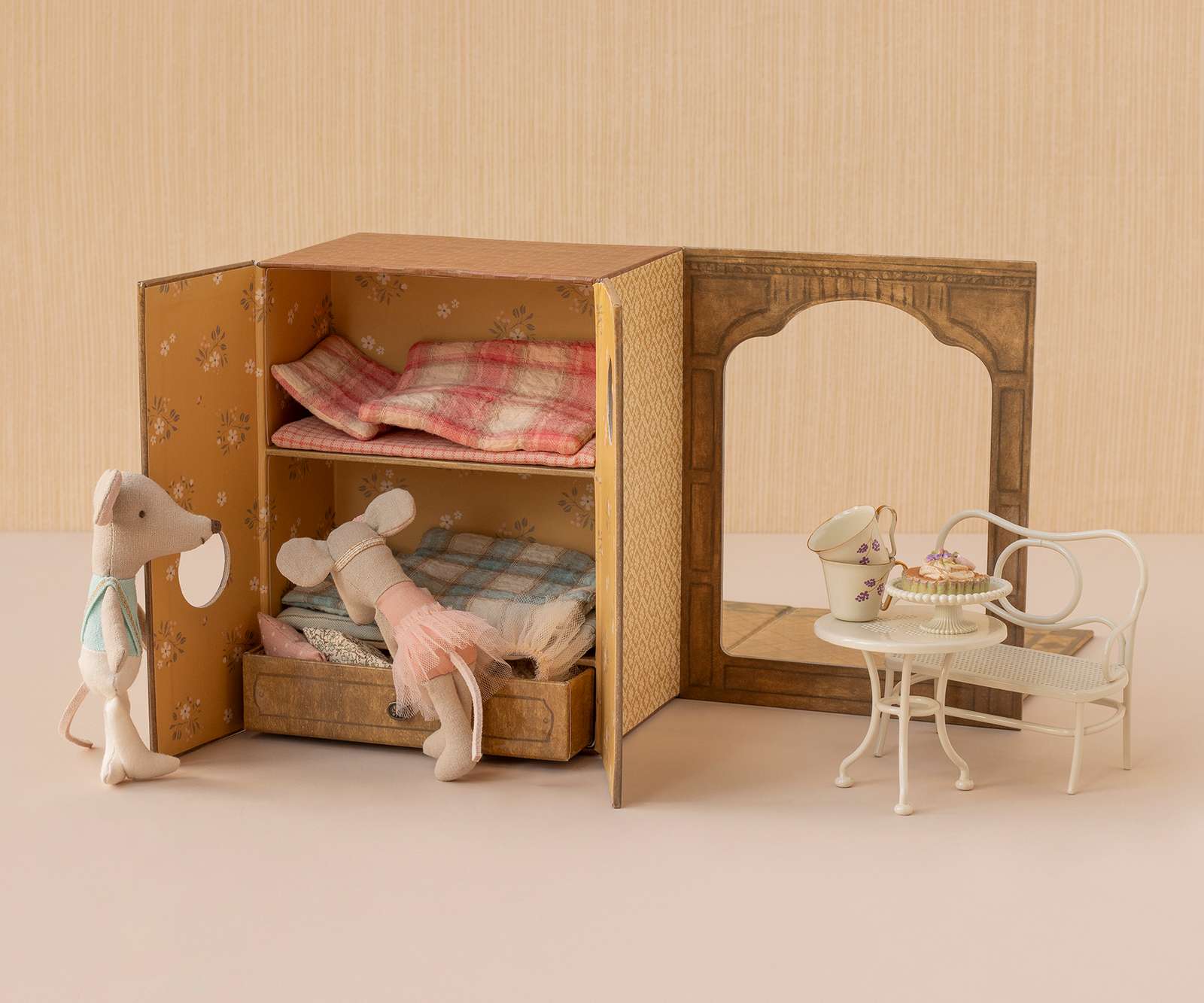 Miniature dollhouse with furniture and plush toys on a neutral background