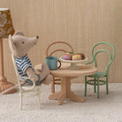 Miniature scene with toy mice around a table in a room with striped wallpaper.