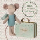 Stuffed mouse toy with a suitcase labeled 'Guardian Angel' on a patterned background with text 'FREE Christmas gift wrap'.