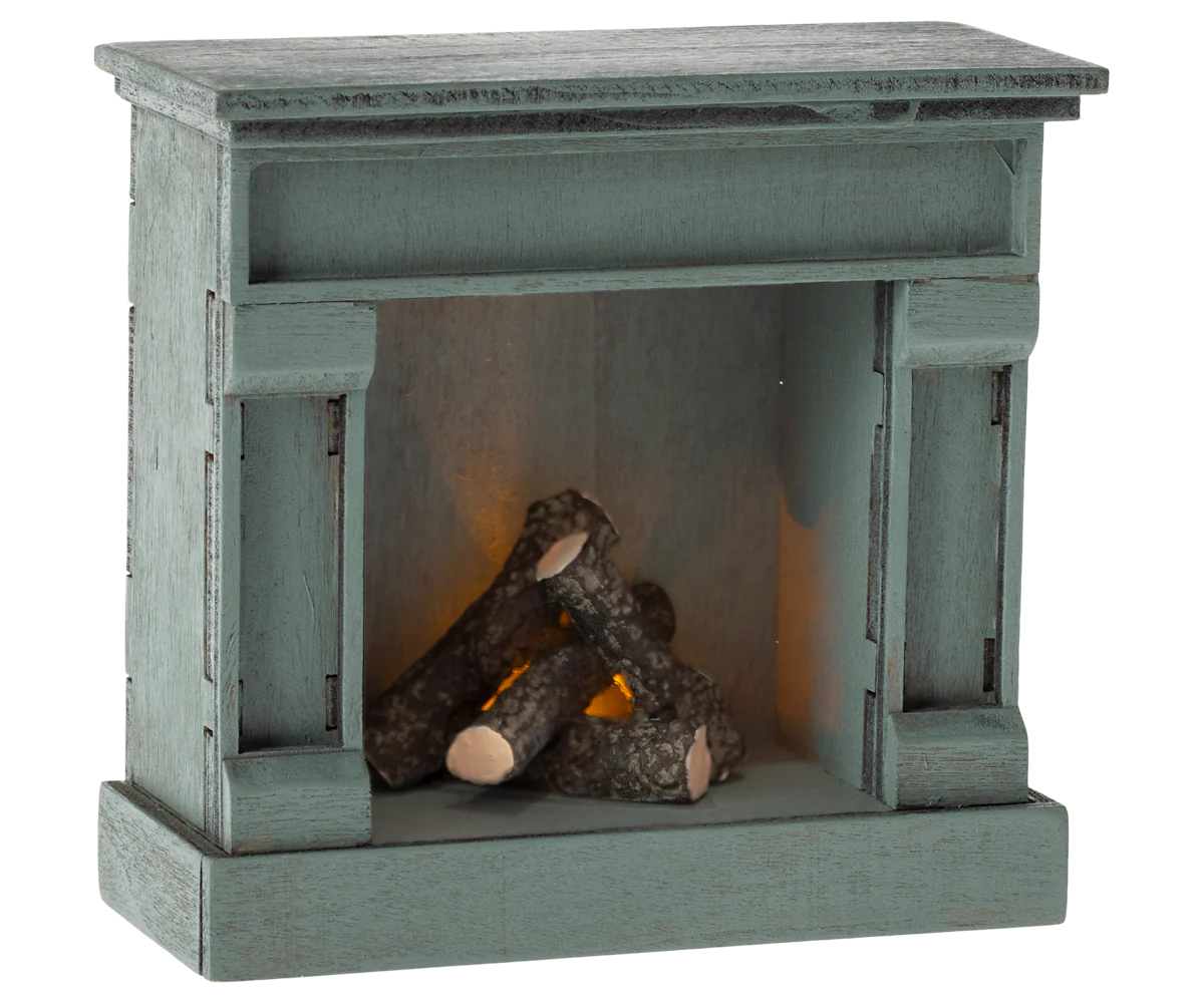 A miniature Maileg wooden fireplace with a vintage blue finish, featuring faux logs inside.