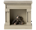 A miniature Maileg wooden fireplace in off-white color with faux logs inside.