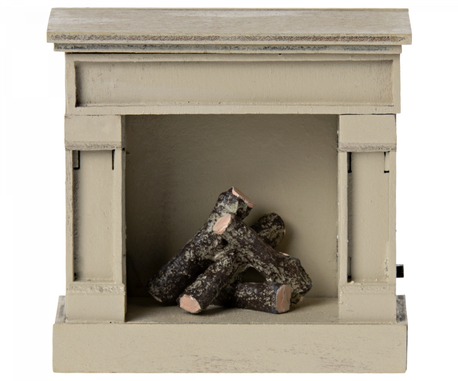 A miniature Maileg wooden fireplace in off-white color with faux logs inside.