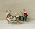 Maileg king queen and prince mice  sitting around a small table against a patterned wall.