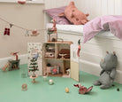 Children's room with a dollhouse, toys, and a bed with pink bedding.