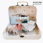 Toy mouse in a miniature room setup inside a suitcase with kitchen and bedroom furniture.
