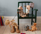 Maileg Poodle plush toys on a chair on a wooden  floor with other toys and books