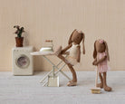 Two Maileg toy bunnies in a domestic setting with a washing machine and ironing board.