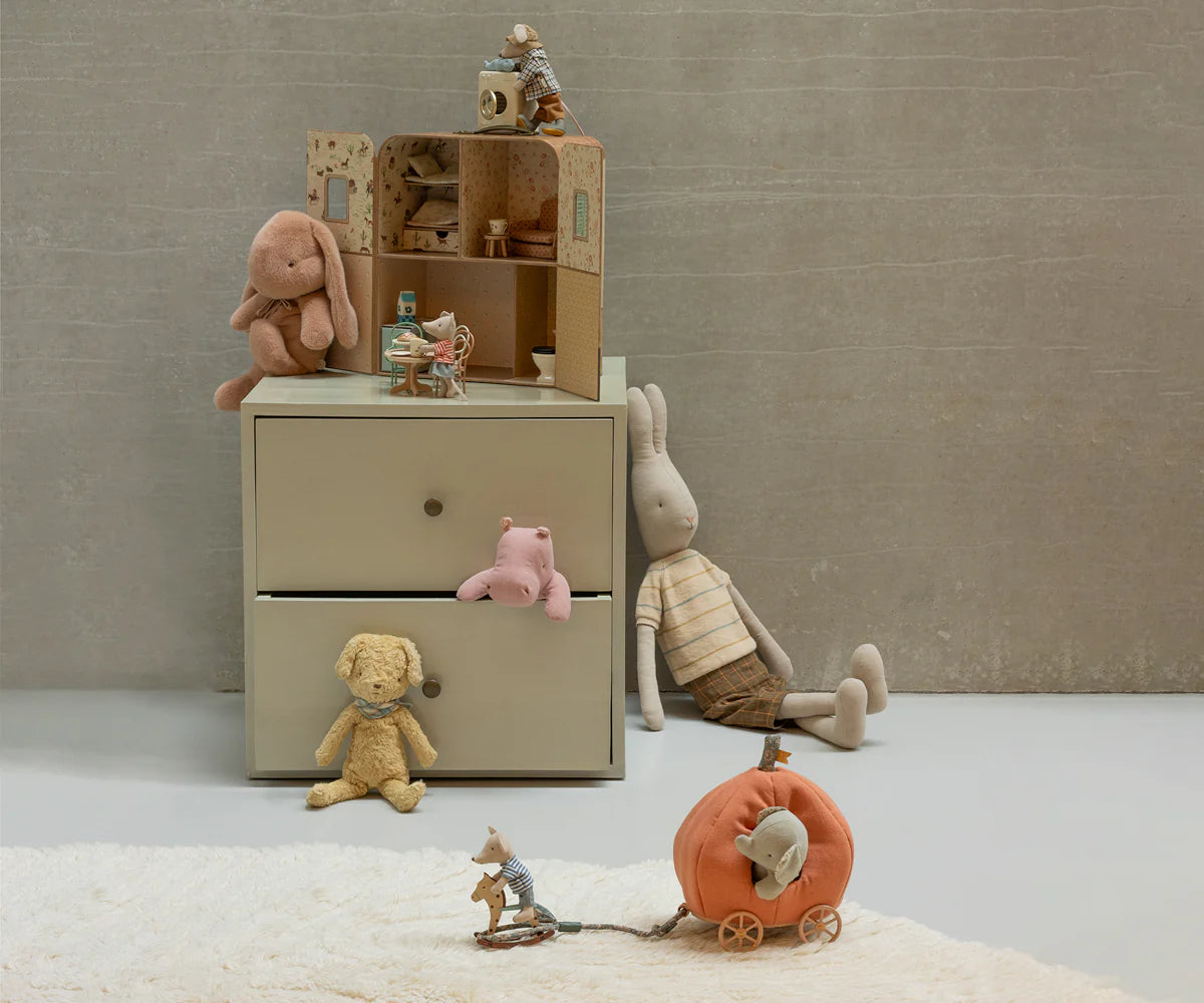 Children's room with a beige dresser, toys, and a pumpkin toy on a light gray floor.