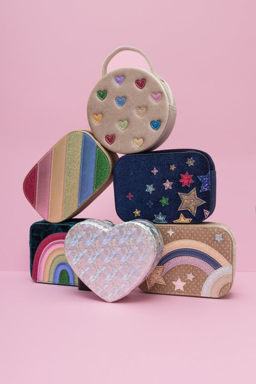 Stack of colorful childrens bags with heart, rainbow, and star designs on a pink background