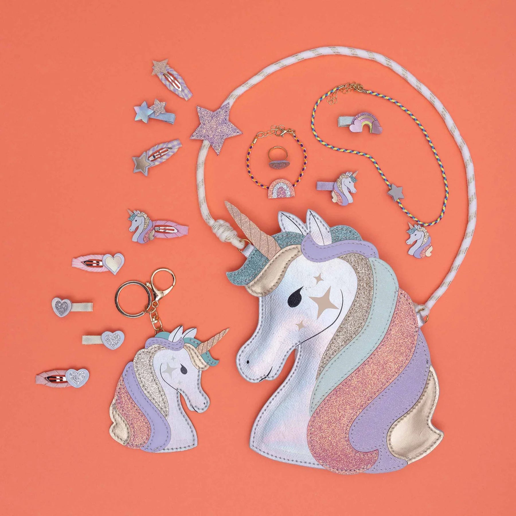 Unicorn-themed accessories including a bag, keychain, and hair clips on an orange background