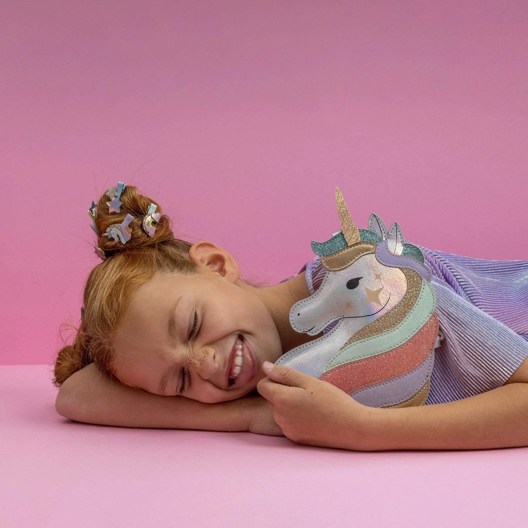 Child holding a unicorn bag against a pink background