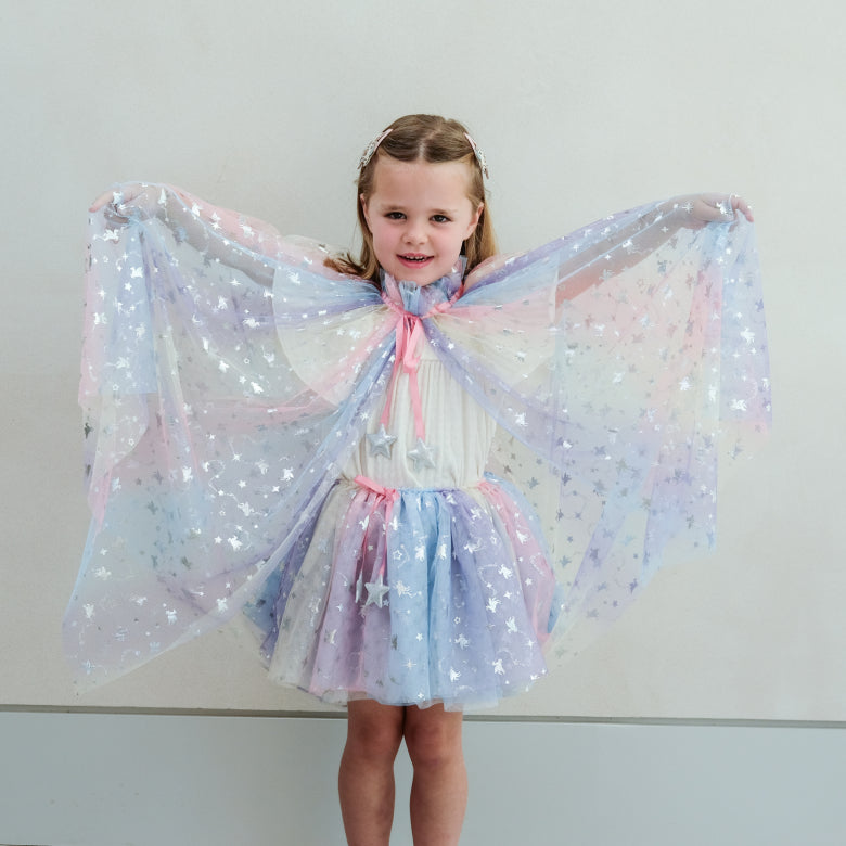 Young girl wearing a star-patterned cape against a plain background