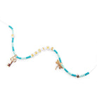 A beaded necklace with turquoise and light blue beads, white letter beads spelling 'ORDINE', gold-tone key and dragonfly charms, and a small gold heart bead on a white background.