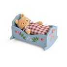 Small wooden bed with a teddy bear and checkered blanket on a white background