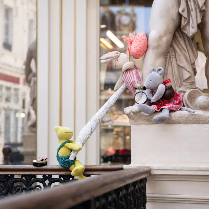 Plush toys on a balcony with a classical statue in the background
