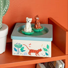 Decorative box with animal illustrations on an orange shelf against an orange wall.