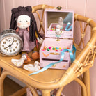Pink jewelry box with mirror, clock, and toys on a wooden chair