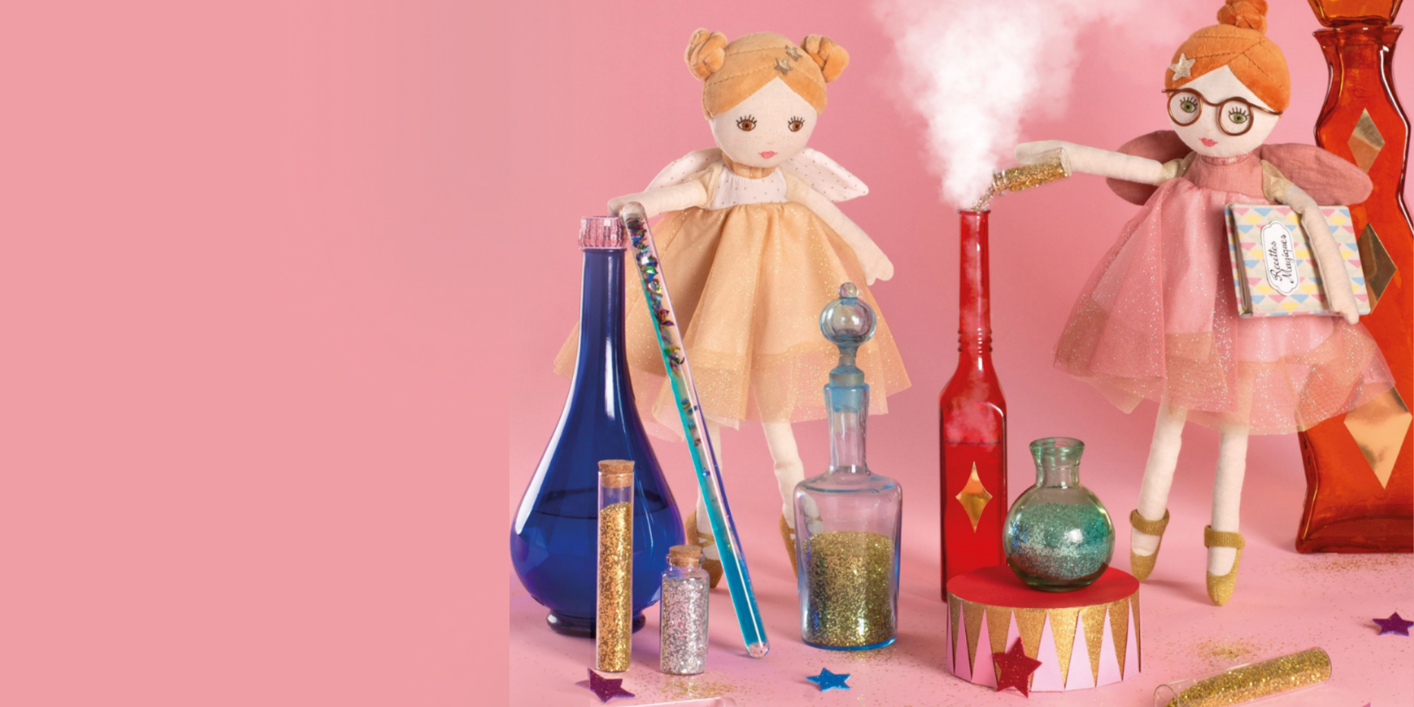 Moulin Roty fairy dolls with laboratory equipment on a pink background