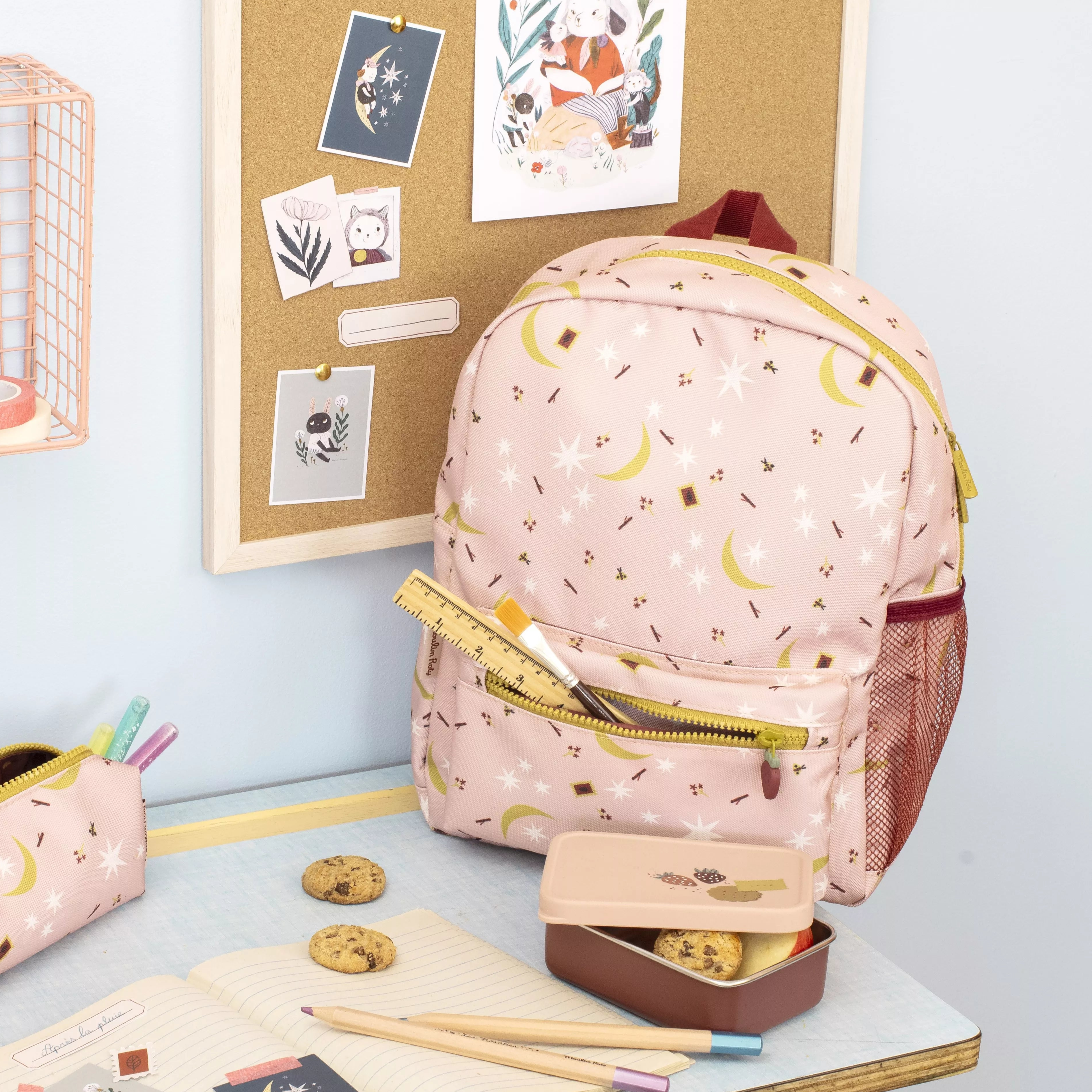 children's Pink backpack and lunchbox on a school desk with stationery items
