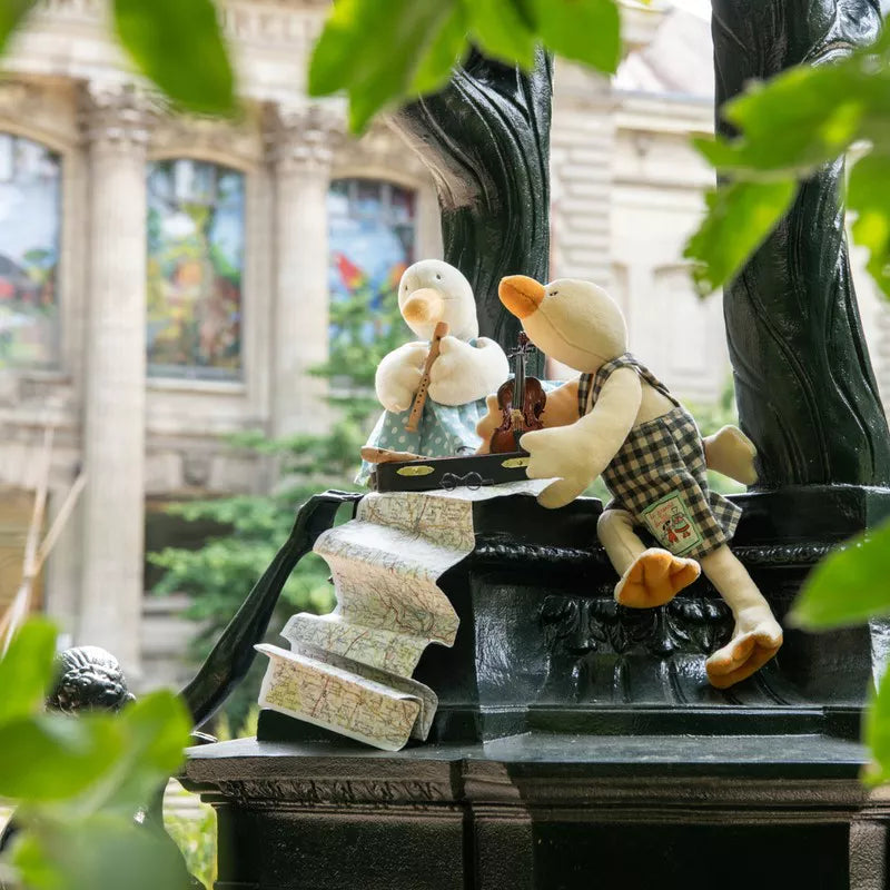 Two toy ducks sitting on a decorative stone structure with a blurred indoor background