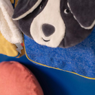 Close-up of a Moulin roty plush dog backpack with a blue background