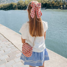 Woman with a large red and white checkered bow by a lake