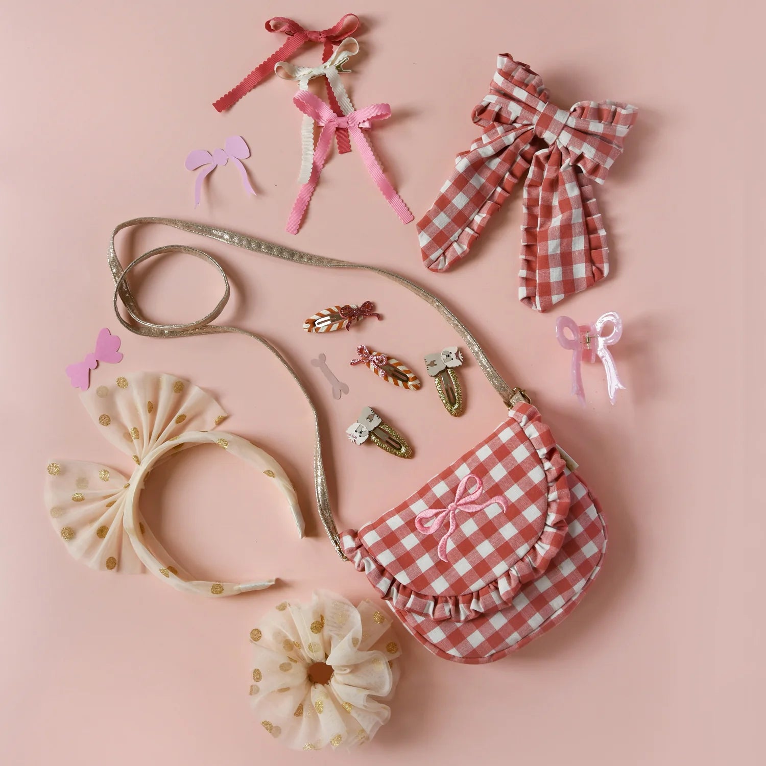 Collection of children's hair accessories including bows and a small bag on a pink background