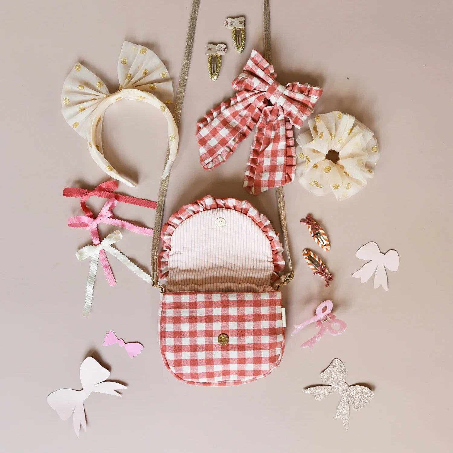 Collection of hair accessories including bows and a small bag on a beige background