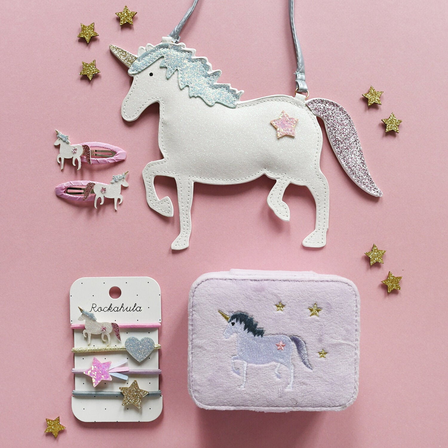 Unicorn-themed accessories including a hanging ornament, hair clips, and a pouch on a pink background.