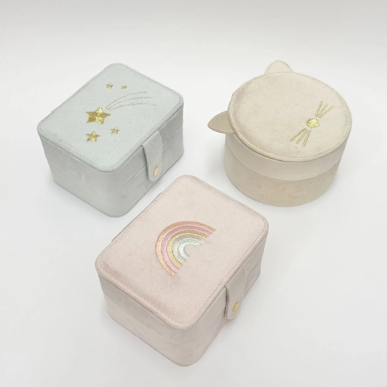 Three embroidered jewelry boxes in different colors on a white background