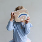 girl holding a bag with a rainbow and star design against a plain background