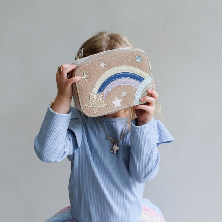 girl holding a bag with a rainbow and star design against a plain background