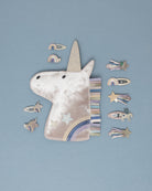 Unicorn-shaped handbag with a strap and unicorn hair clips on a blue background