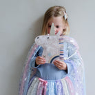 Child holding a unicorn-shaped handbag with a starry night design, wearing a colorful cape.