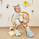 Child sitting in a chair with plush toys in a room with decorative flowers on the wall.