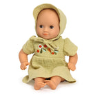 Baby doll wearing a green dress with floral embroidery on a white background