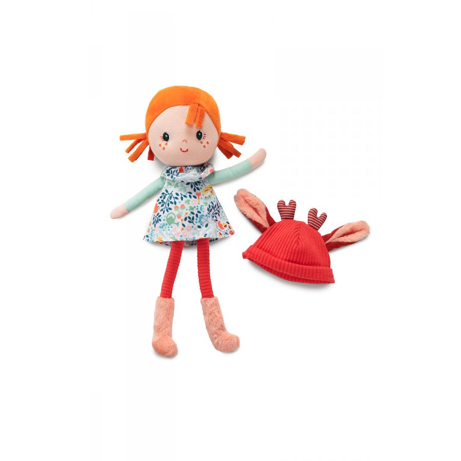 Stuffed doll with red hair and floral dress next to a red hat on a white background