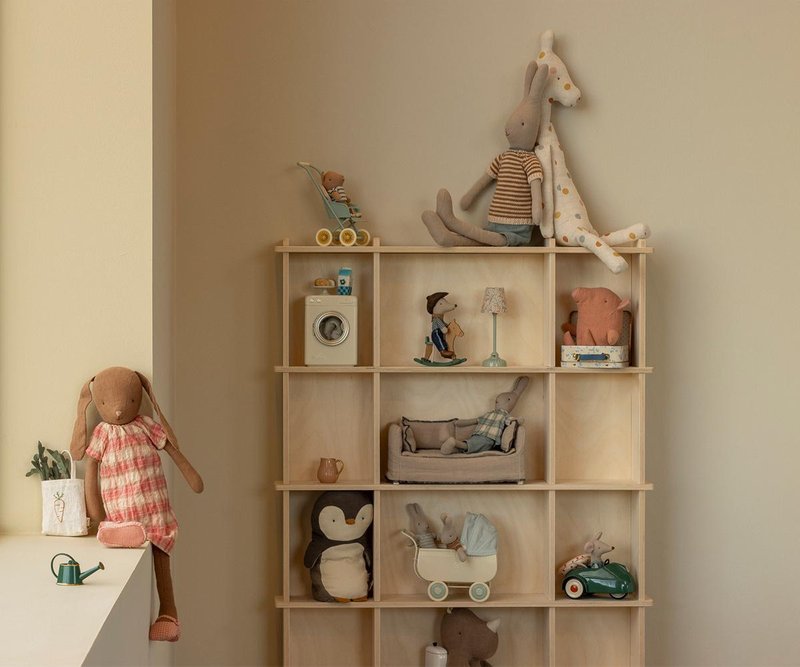 Wooden shelf with various toys and decorative items against a beige wall.