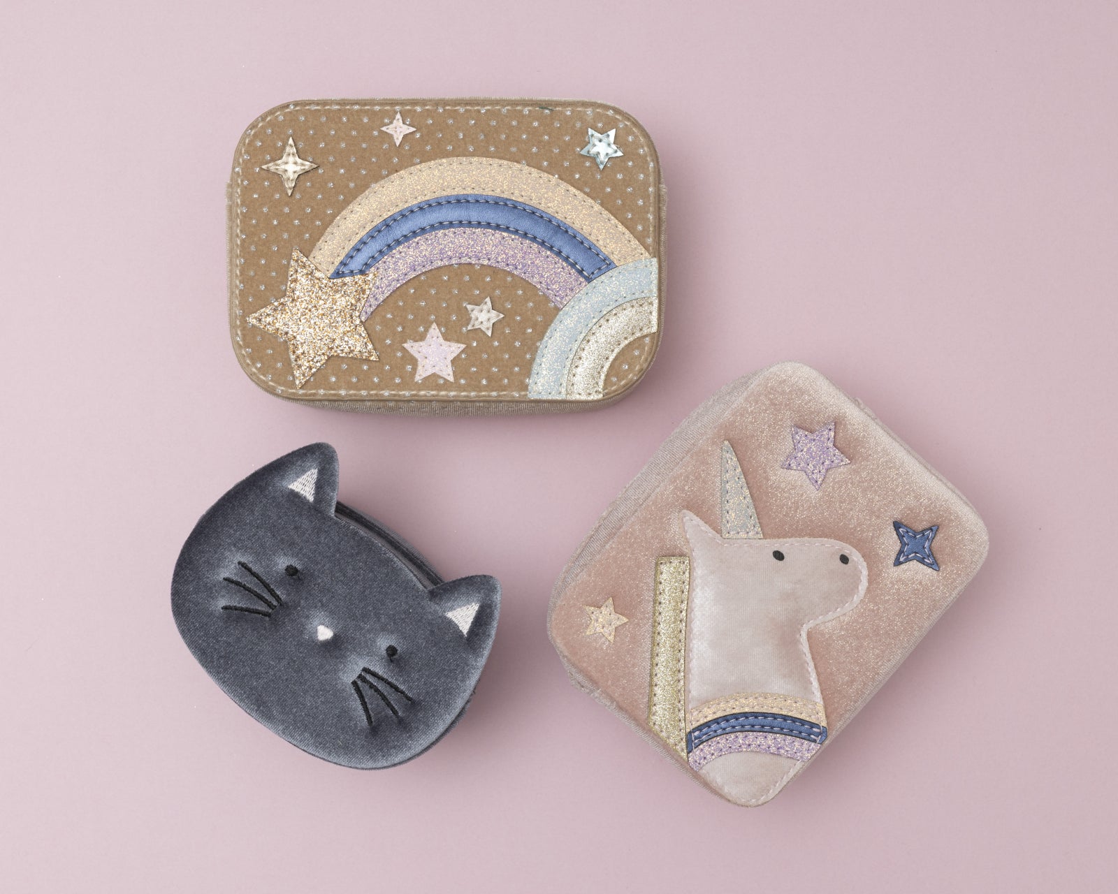 Three decorative childrens handbags with cat, rainbow, and unicorn designs on a pink background