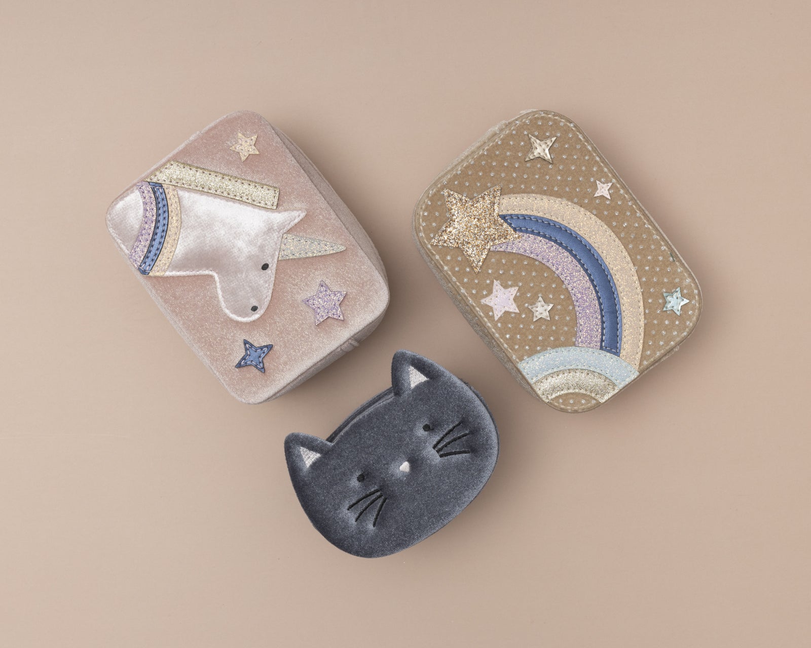 Three small decorative childrens bags with unicorn, cat, and rainbow designs on a beige background