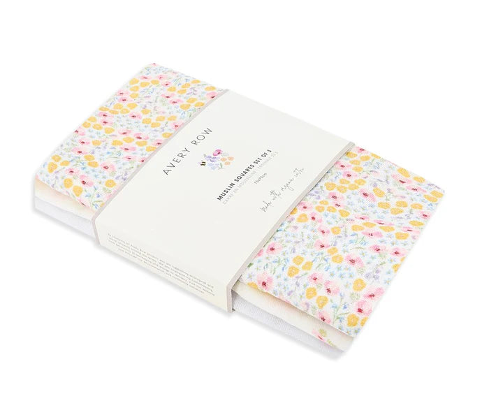A set of three folded organic cotton muslin squares with a floral pattern, packaged together with a branded band.