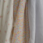 Three types of fabric muslin cloths with floral patterns hanging together.
